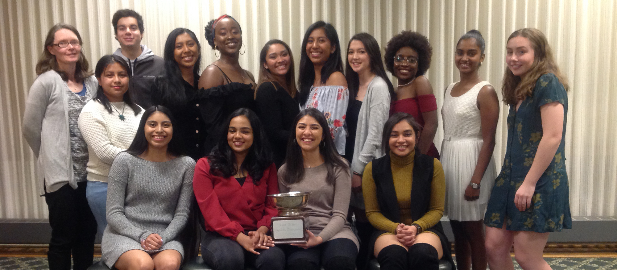 Photo of the Lyons squash team, both players and coaches, posing for a photo following their win after the 2019 Seven Sisters Championship.